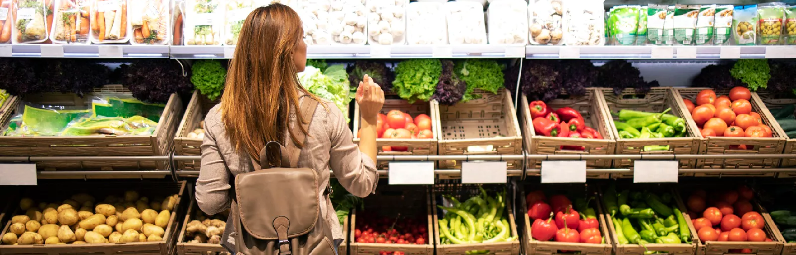 Female customer examining items in a grocery aisle.